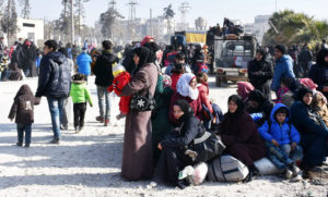 Syryjscy cywile czekający w punkcie kontrolnym obsadzonym przez siły prorządowe, na rondzie ulicy al-Hawoz, po opuszczeniu w sobotę wschodnich dzielnic Aleppo. (AFP)